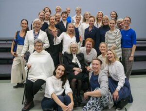 Iloiset eri-ikäiset ihmiset ovat asettautuneet ryhmäkuvaan portaiden eteen.